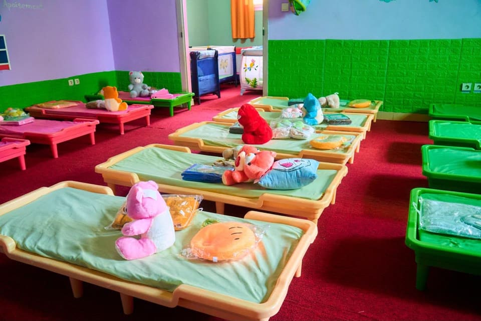 Le dortoir : des petits lits alignés, chacun préparé avec une couverture et une peluche.