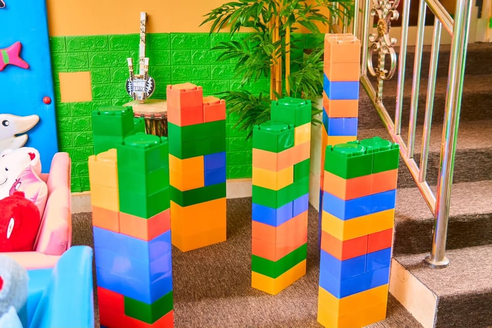 Des tours assemblées en briques de construction géantes, dans un espace de jeu de l’école.
