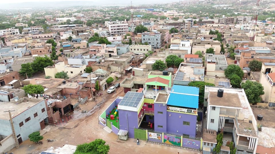 Vue aérienne de l’école : le bâtiment aux façades colorées et son aire de jeux, dans le quartier de Yirimadjo Zerny à Bamako.